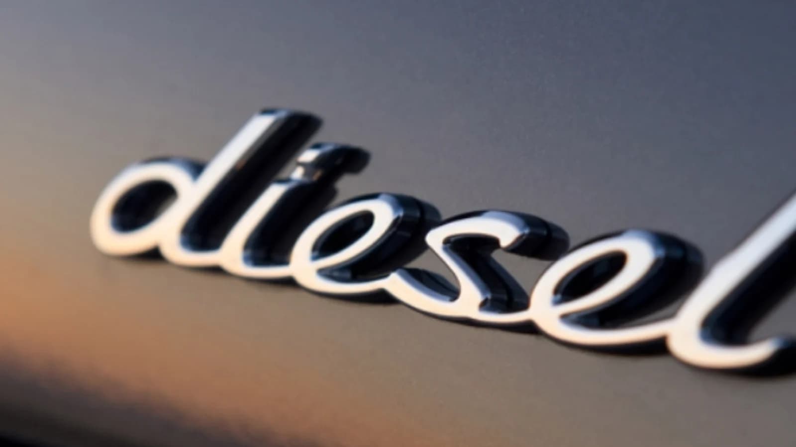 Fotografia del logo diesel cromato su una carrozzeria bianca.