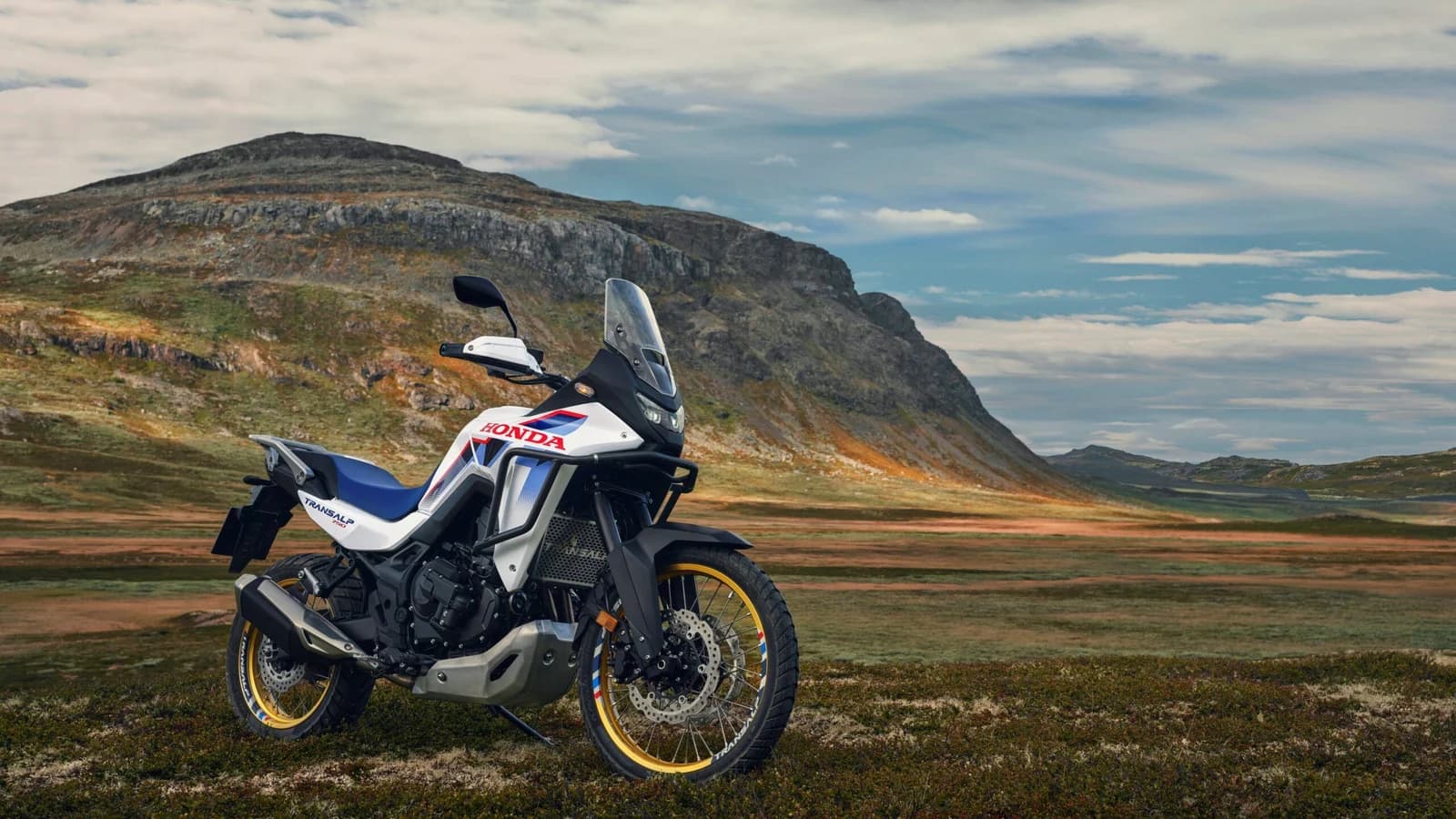 Honda XL750 Transalp in un paesaggio di montagna, con un motociclista in sella.