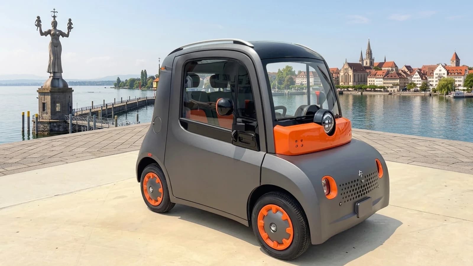 Microcar Astraux grigia a due posti parcheggiata vicino a un lungomare cittadino.