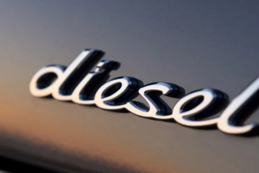 Fotografia del logo diesel cromato su una carrozzeria bianca.