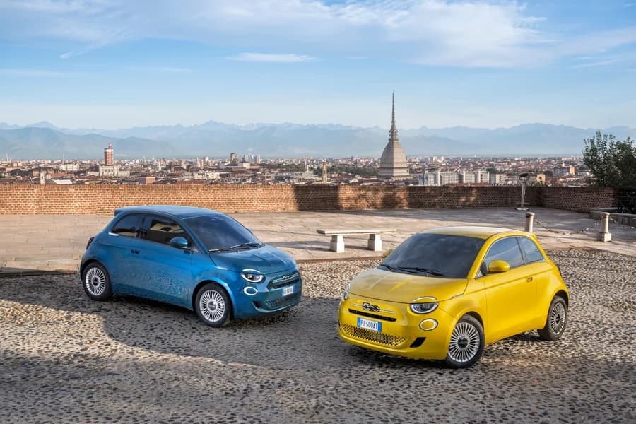 Fiat 500 ibride azzurra e gialla parcheggiate in una piazza cittadina.
