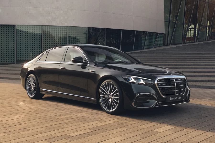 Mercedes Classe S nera parcheggiata davanti a un edificio moderno.