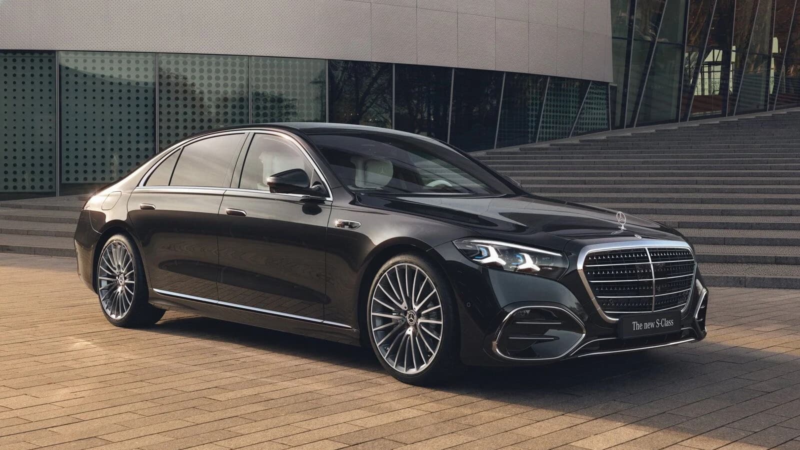 Mercedes Classe S nera parcheggiata davanti a un edificio moderno.